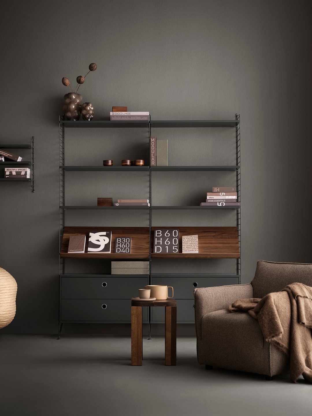 Modern interior with a metal shelving unit against a dark wall, featuring books and decorative items.