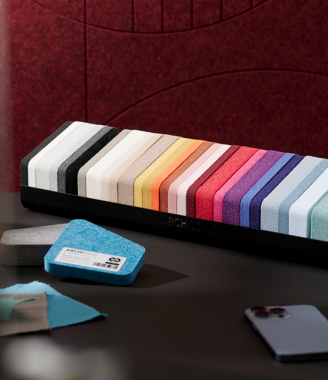 Colorful striped fabric roll with a blue fabric swatch on a dark surface.