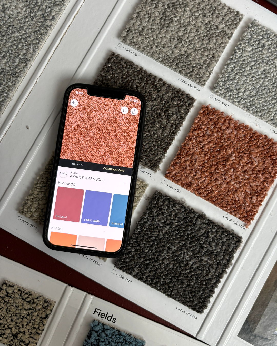 Moodboard of different coloured fabric and smartphone showing colours in NCS+ app