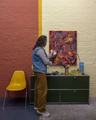Mike Klar holding up the trend fan deck 2025+ against his painting in the colours of Inner